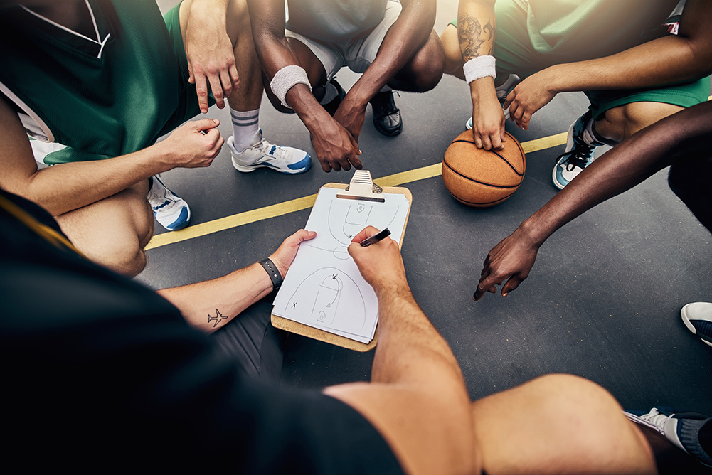 Basketball, strategy and team with a sports coach talking to a team while planning tactics on a clipboard and hands. Teamwork, fitness and exercise with a player and teammates listening at training.