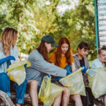 Group of activists friends collecting plastic waste at the park. People cleaning the park up, with bags.