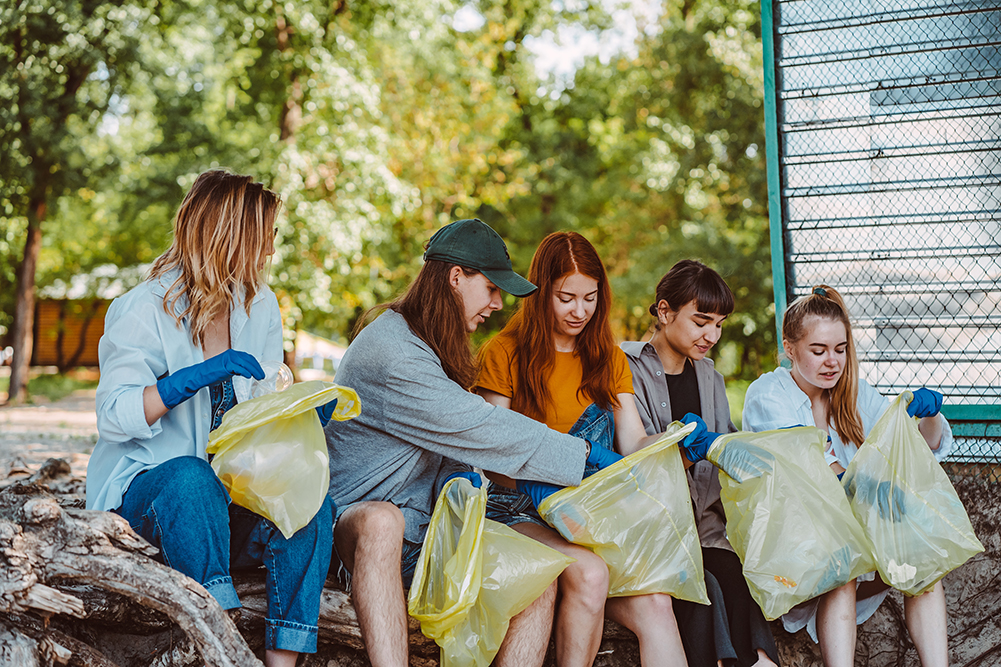 Group of activists friends collecting plastic waste at the park. People cleaning the park up, with bags.