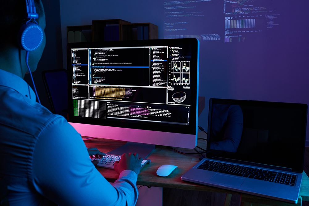 Programmer in headphones checking his code on computer screen