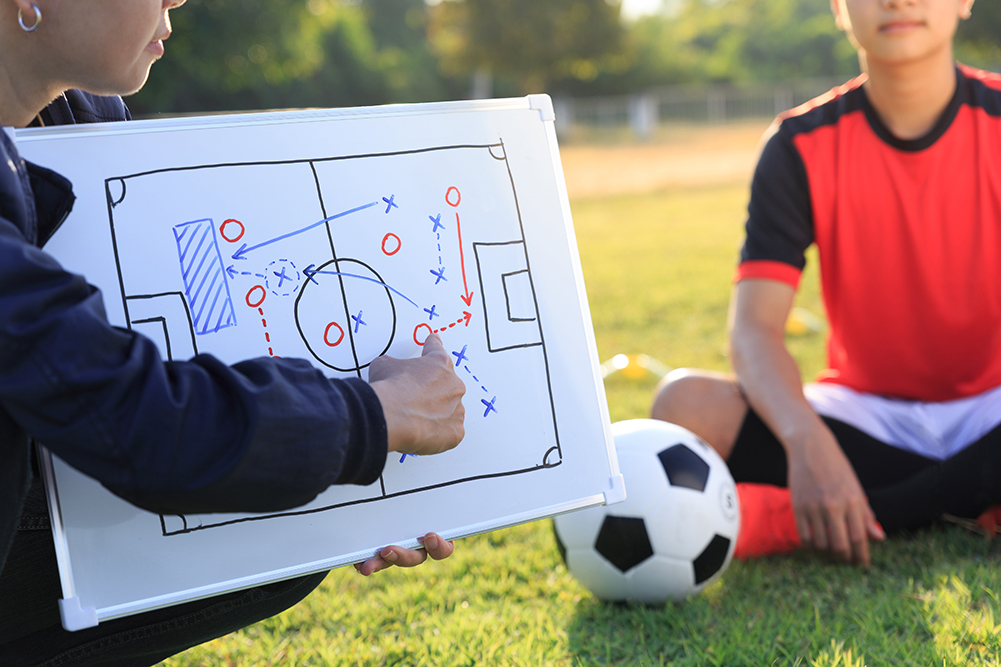 Coach training a tactic for asian teenager football player.